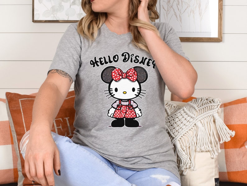 May include: Gray t-shirt with a cartoon image of Hello Kitty wearing a red bow and a red and white polka dot dress. The text "HELLO DISNEY" is printed above the image.