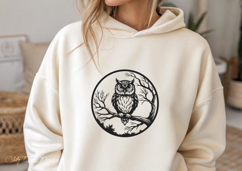 Puede incluir: Una sudadera con capucha blanca con un gr&aacute;fico en blanco y negro de un b&uacute;ho posado en una rama dentro de un c&iacute;rculo. El b&uacute;ho tiene ojos grandes y redondos y plumas detalladas.