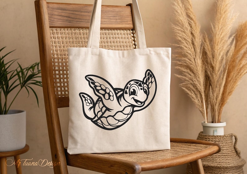 Pu&ograve; includere: Una borsa tote in tela bianca con un'illustrazione in bianco e nero di una tartaruga dei cartoni animati con un viso sorridente. La tartaruga sta nuotando con le pinne distese.