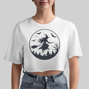 May include: White cropped t-shirt with a black and white graphic of a witch flying on a broomstick in front of a full moon with bats and trees.