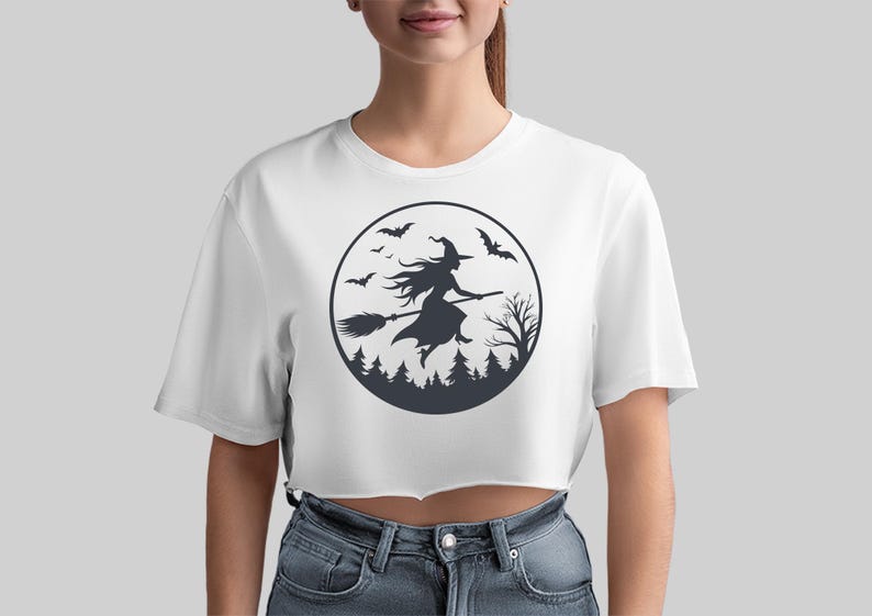 May include: White cropped t-shirt with a black and white graphic of a witch flying on a broomstick in front of a full moon with bats and trees.