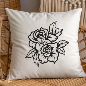May include: A white pillow with a black silhouette of two roses and leaves. The roses are in full bloom and have a classic design.