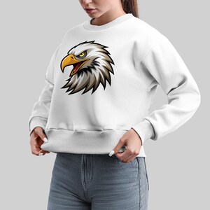 May include: White sweatshirt with a cartoon eagle head graphic. The eagle has a yellow beak and eyes.