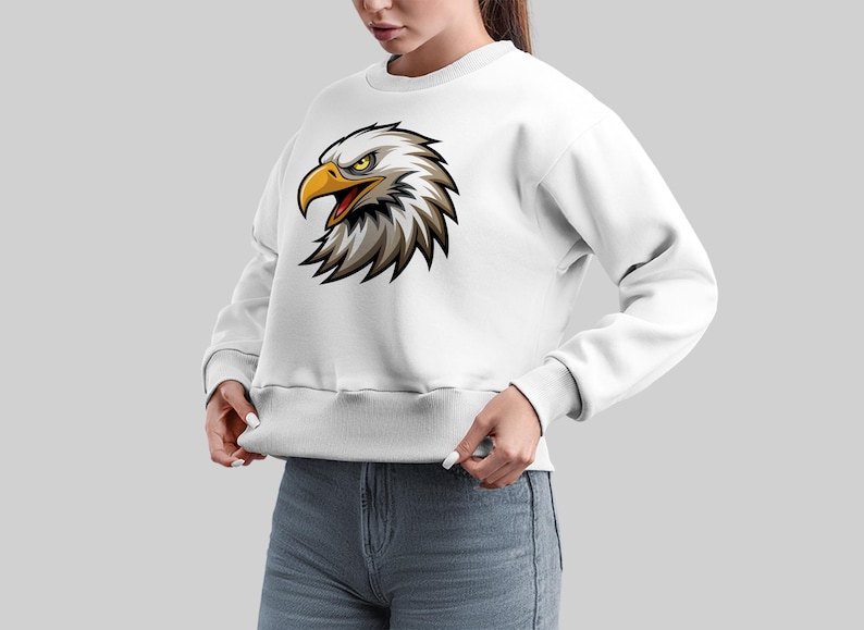 May include: White sweatshirt with a cartoon eagle head graphic. The eagle has a yellow beak and eyes.