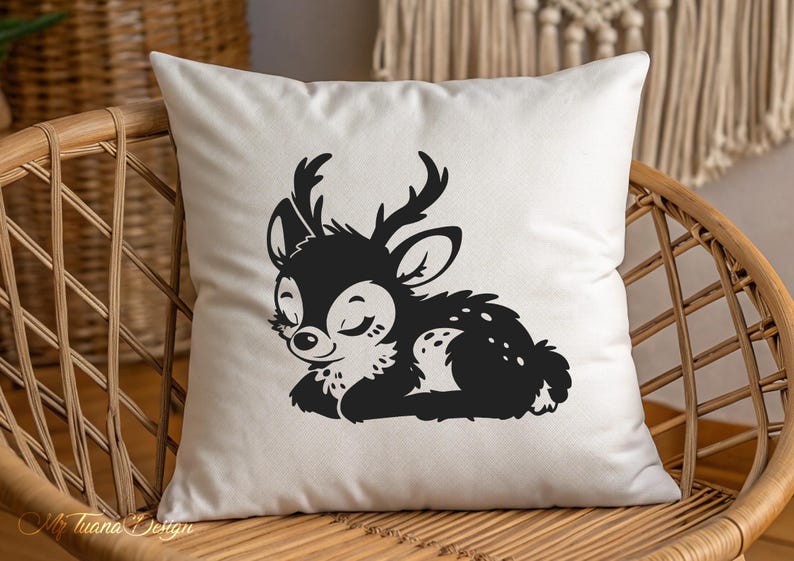 May include: A white pillow with a black silhouette of a sleeping fawn with closed eyes and antlers. The fawn is lying on its side with its head resting on its front paws.
