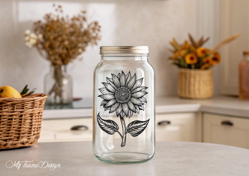 Puede incluir: Un tarro de vidrio transparente con un dise&ntilde;o de girasol en blanco y negro. El tarro tiene una tapa plateada y est&aacute; sentado en una mesa blanca.