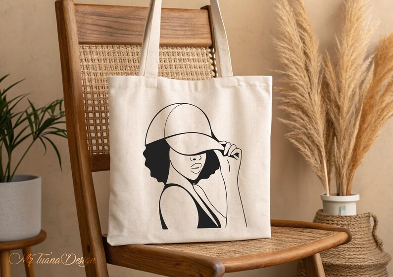 May include: A white tote bag with a black line drawing of a person wearing a baseball cap. The person is looking to the side and has their hand up to their face.