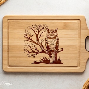 Puede incluir: Una tabla de cortar de madera con un b&uacute;ho marr&oacute;n posado en una rama de &aacute;rbol. El b&uacute;ho tiene un dise&ntilde;o detallado y est&aacute; rodeado de hojas. La tabla de cortar tiene un asa en el lateral.