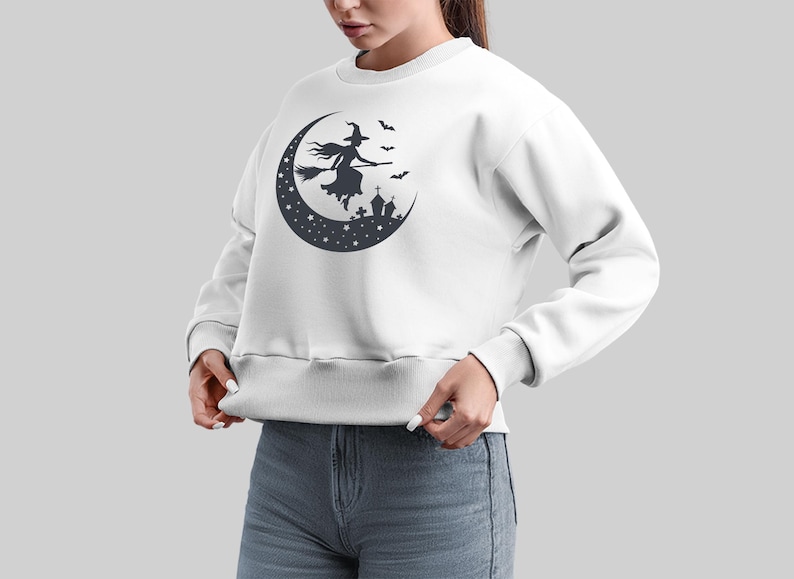 May include: White sweatshirt with a black silhouette of a witch flying on a crescent moon with stars and bats.