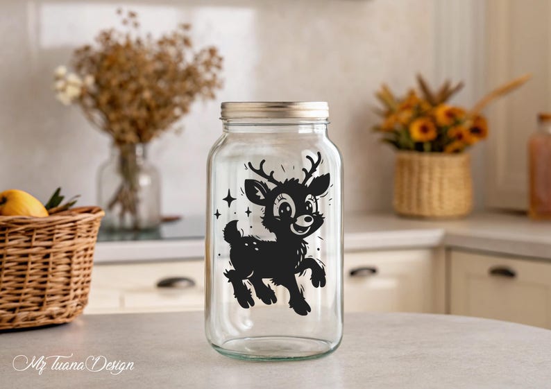 May include: A clear glass jar with a black and white silhouette of a deer with antlers. The deer is looking to the right and has a happy expression. The jar has a silver lid.