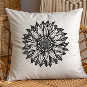 Puede incluir: Una almohada blanca con un dibujo en blanco y negro de un girasol. La almohada est&aacute; sentada en una silla de mimbre.