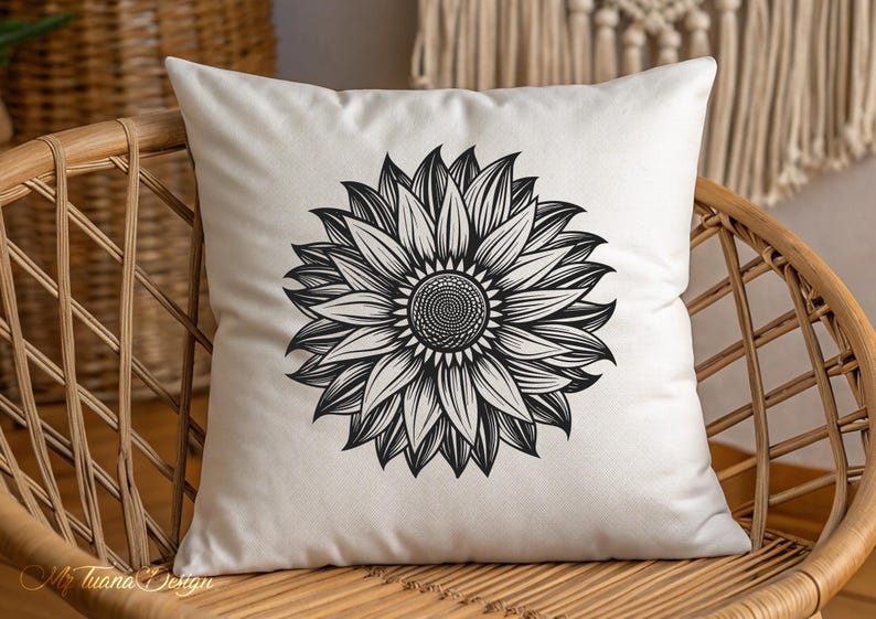 Puede incluir: Una almohada blanca con un dibujo en blanco y negro de un girasol. La almohada est&aacute; sentada en una silla de mimbre.