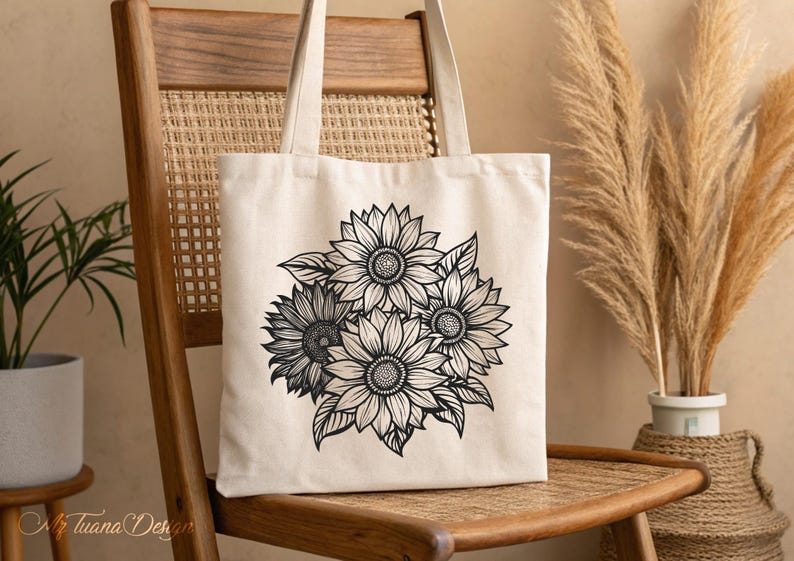 Puede incluir: Una bolsa de lona blanca con una ilustraci&oacute;n en blanco y negro de un ramo de girasoles. La bolsa tiene un asa larga y est&aacute; sentada en una silla de madera.