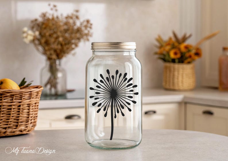 May include: A clear glass jar with a silver lid and a black dandelion silhouette decal. The jar is sitting on a white countertop.