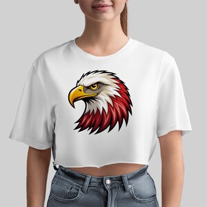 May include: White cropped t-shirt with a cartoon image of an eagle's head with red, white, and yellow feathers.