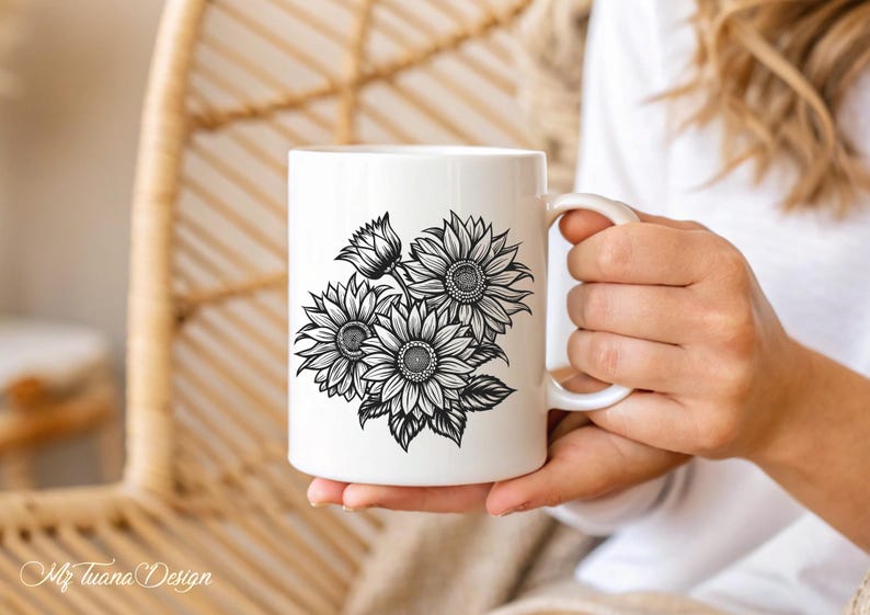 Puede incluir: Taza de cer&aacute;mica blanca con un dibujo en blanco y negro de girasoles. La taza est&aacute; siendo sostenida por la mano de una persona.