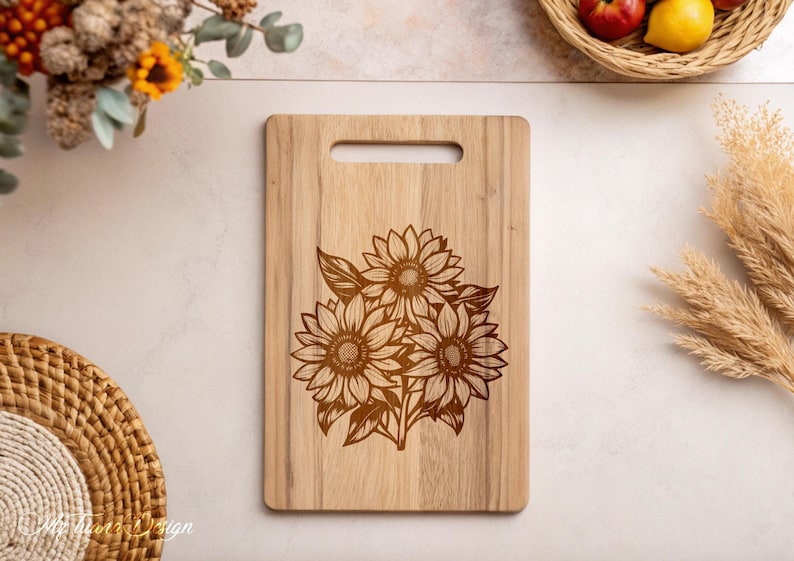 Puede incluir: Una tabla de cortar de madera con un dise&ntilde;o de tres girasoles grabado con l&aacute;ser. Los girasoles son marrones y tienen un dise&ntilde;o detallado.