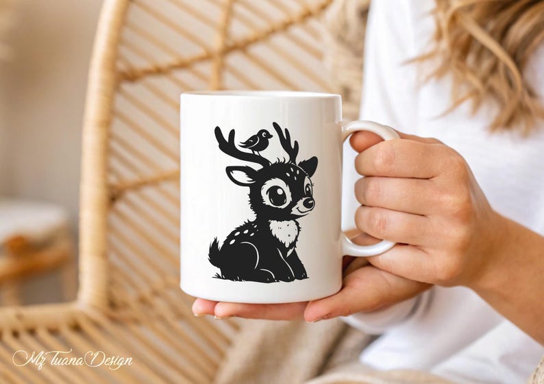 May include: White ceramic mug with a black silhouette of a deer with a bird on its head. The deer has large eyes and is sitting down.