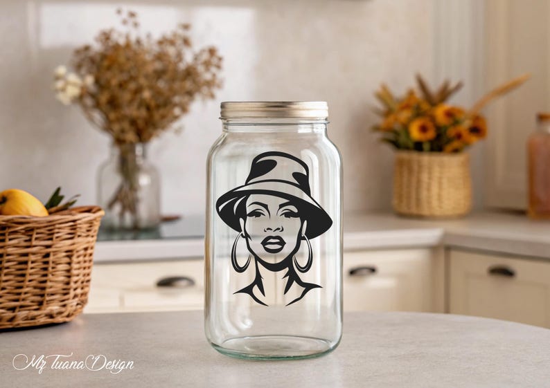 May include: A clear glass jar with a black and white silhouette of a woman wearing a hat and large earrings. The jar has a silver lid.