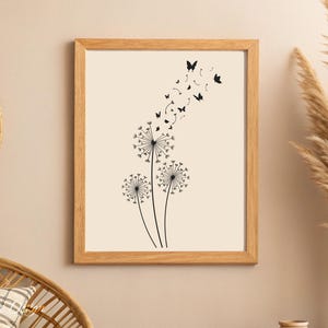 May include: A black and white print of three dandelions with butterflies flying away from them. The print is framed in a light wood frame.