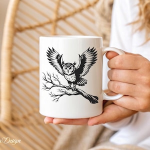 Puede incluir: Taza de cer&aacute;mica blanca con una ilustraci&oacute;n en blanco y negro de un b&uacute;ho con las alas extendidas, posado en una rama.