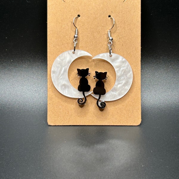 Cat sitting on moon dangly earring.