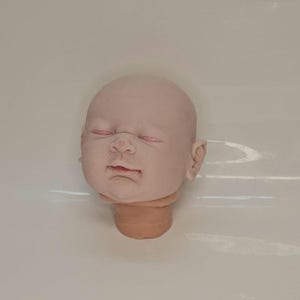 Pu&ograve; includere: Una testa di bambola in vinile non dipinta dalla pelle chiara, con occhi chiusi caratterizzati da una sottile sfumatura rosa sulle palpebre, un naso piccolo e labbra leggermente socchiuse. La testa &egrave; liscia, calva e include un breve collo.