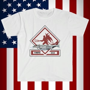 May include: White t-shirt with a red and white graphic of a fighter jet with the words "VMFA 232" and "MARINES" on it. The graphic also includes a red devil with a trident.