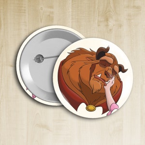 May include: A round button featuring a cartoon illustration of the Beast from Beauty and the Beast. The Beast is shown with his eyes closed and a hand gently touching his cheek. The background is white.