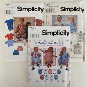 May include: Three vintage Simplicity sewing pattern envelopes for baby clothes. The patterns feature illustrations of babies in various outfits, including rompers, dresses, and shorts. The envelopes are white with black text and colorful illustrations.