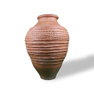 May include: A terracotta-colored, handcrafted vase with a wide, rounded body and a narrow neck. The vase features horizontal, textured bands that encircle the vessel. The base has a darker, earthy tone, and the vase casts a shadow.