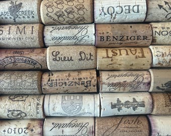 May include: A close-up of a collection of wine corks with various winery names and logos printed on them, including "Hall", "Hess Collection", "Decoy", "Benziger", "Faust", "Simi", "Cape Creek Vineyards", "Raymond Vineyards", "Liev Dit", "Textbook", "2021 Alexander Valley", "Josh", "Seaulieu", "Kruetz", and "Tattamacca".