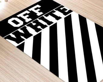 Pode incluir: Tapete listrado preto e branco com as palavras "OFF WHITE" em letras brancas.