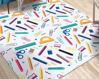 May include: A white rug with a colorful pattern of school supplies, including pencils, rulers, scissors, paper clips, and protractors.
