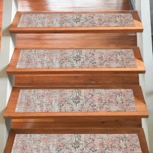 May include: Stair treads with a distressed, patterned design in red, beige, and navy blue. The treads are placed on wooden stairs, creating a contrast between the aged design and the natural wood. The image shows a close-up of the steps.