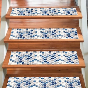 May include: Wooden staircase with four steps, each adorned with a runner featuring a blue, gray, and white geometric honeycomb pattern. The steps are made of warm-toned wood, creating a contrast with the cool colors of the runners.