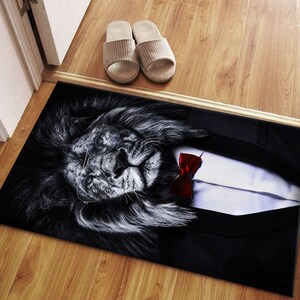 May include: A black and white doormat with a lion wearing a tuxedo and bow tie. The lion is wearing glasses and has a serious expression.