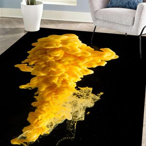 Puede incluir: Alfombra de arte abstracto con un diseño de nube de tinta amarilla sobre un fondo negro.