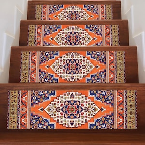 May include: Stair treads with an ornate, patterned design. The treads feature a central diamond-shaped motif in white, red, and navy blue, set against an orange background. The edges have a detailed border with complementary colors. The treads are installed on wooden stairs.