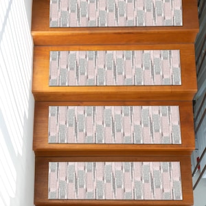 May include: Wooden staircase with four steps, each adorned with a rectangular stair tread. The treads feature a repeating pattern of pink, gray, and white vertical stripes, creating a textured appearance. The wood of the stairs is a warm, natural tone.