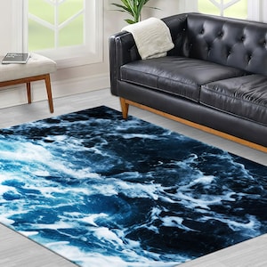 May include: A blue and white area rug with a wave pattern. The rug is in a living room setting with a black leather sofa.