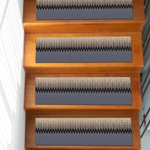 Puede incluir: Escalera de madera con cuatro escalones, cada uno con una huella rectangular. Las huellas tienen una base gris oscuro con un patrón degradado texturizado marrón claro y gris y un borde en zigzag negro. Los escalones son de madera marrón claro.
