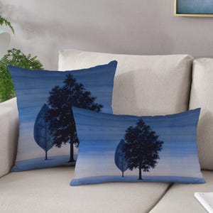 May include: Two blue throw pillows with a watercolor design of trees silhouetted against a blue sky.