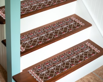 Puede incluir: Peldaños de escalera con un patrón geométrico marrón, rojo y blanco. Las huellas están instaladas en escalones de madera con contrahuellas blancas. El diseño presenta un motivo repetitivo de diamantes y flores, agregando un elemento decorativo a la escalera.