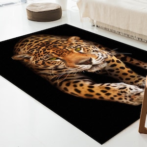 May include: A close-up of a jaguar's face with a black background. The jaguar has a spotted coat and is looking directly at the camera.