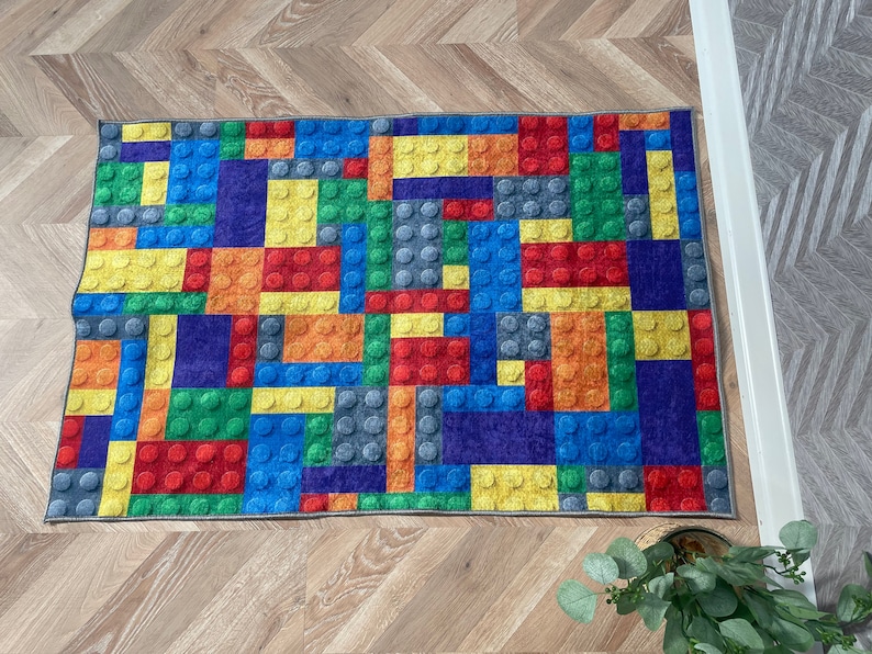May include: A colorful rug with a design that resembles a pattern of colorful toy building blocks. The rug is made of a soft, plush material and is perfect for adding a playful touch to any room.