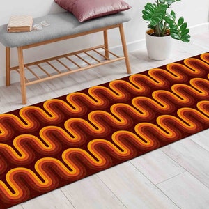 Op de afbeelding: Een lang, smal looptapijt met een retro-patroon van golvende lijnen in tinten oranje, geel en bruin. Het tapijt ligt op een lichte houten vloer.