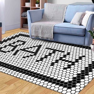 May include: Black and white geometric area rug with a hexagonal pattern. The rug is in a living room setting with a couch and a side table.