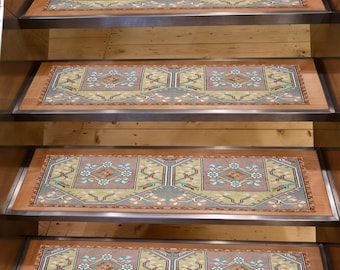 Puede incluir: Un juego de peldaños de escalera con un diseño de alfombra tradicional. Las alfombras presentan un patrón de diamante central en tonos de rosa, verde y azul, enmarcados por un borde de colores similares. Los peldaños están colocados en escaleras de madera.