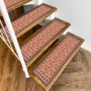 May include: Stair treads with a floral pattern in shades of peach, brown, and cream. The treads are rectangular and bordered with a darker brown trim. The stairs are made of wood and have a white railing.